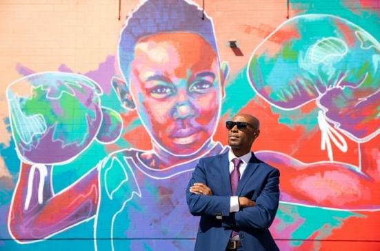 man in sunglasses in front of colorful mural